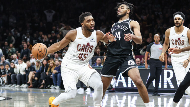 A fan rushes onto the court and rushes Donovan Mitchell in Brooklyn